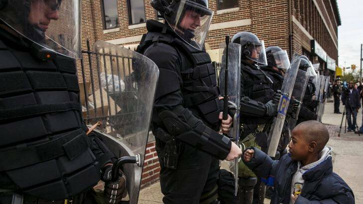 A young boy greets police officers in riot gear during a march in Baltimore after the decision to charge six officers, including one with murder. Photo: LUCAS JACKSON/Reuters