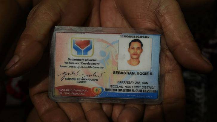 A relative of Rogie Sebastian holds his ID card.  Photo: Kate Geraghty