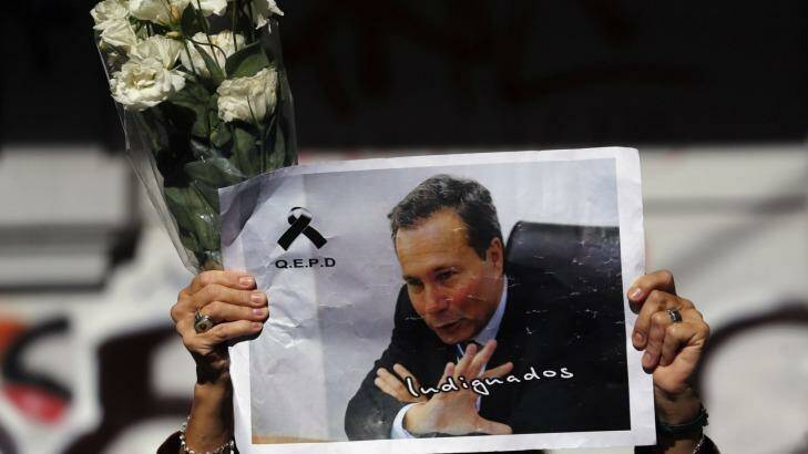 A woman holds up flowers and an image of late prosecutor Alberto Nisman while waiting for the hearse with his remains, in Buenos Aires January 29, 2015. Photo: Supplied
