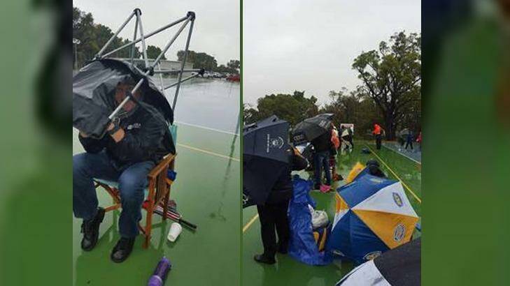 Spectators take cover at the netball on Sunday as youngsters are forced to play on. Photo: Supplied