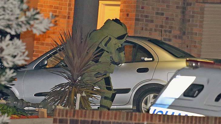A police officer in a bomb suit inspects the car at the scene. Photo: Getty Images/Scott Barbour