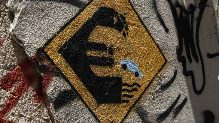 Graffiti depicting a car driving off a euro sign into water on a wall of an abandoned house in Athens. Photo: Yorgos Karahalis/AP