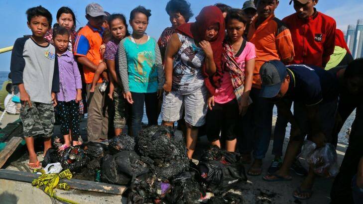 People at Muara Angke Port in Jakarta, Indonesia, inspect charred personal belongings of passengers on a ferry that caught fire. Photo: AP/Dita Alangkara