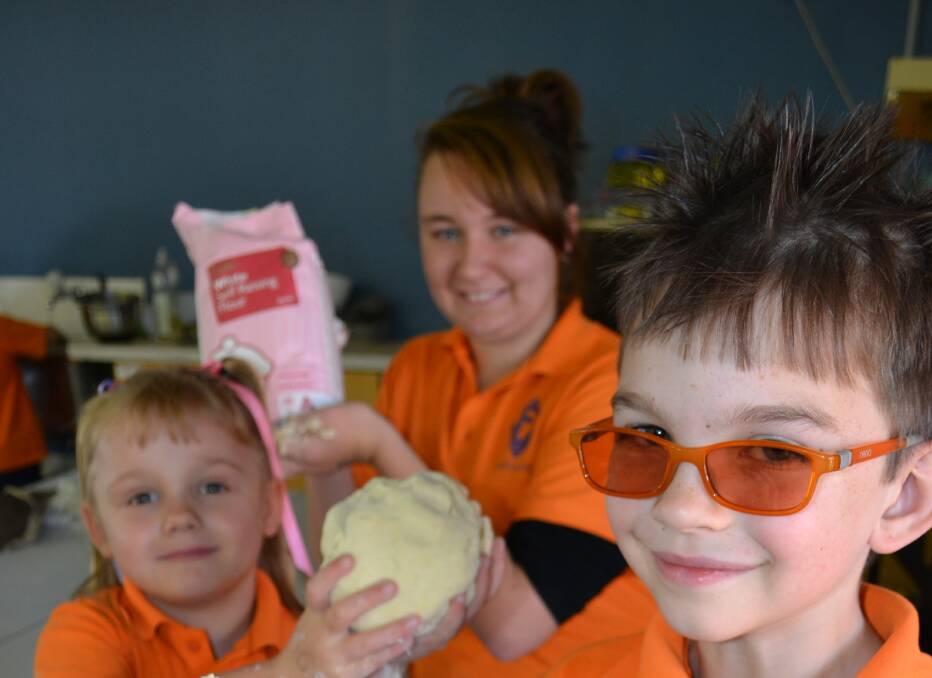 Messy fun: Fairview students Charlee Gribble, Tamieka Swallow and Jack Storen have fun celebrating NAIDOC week with damper mix.
