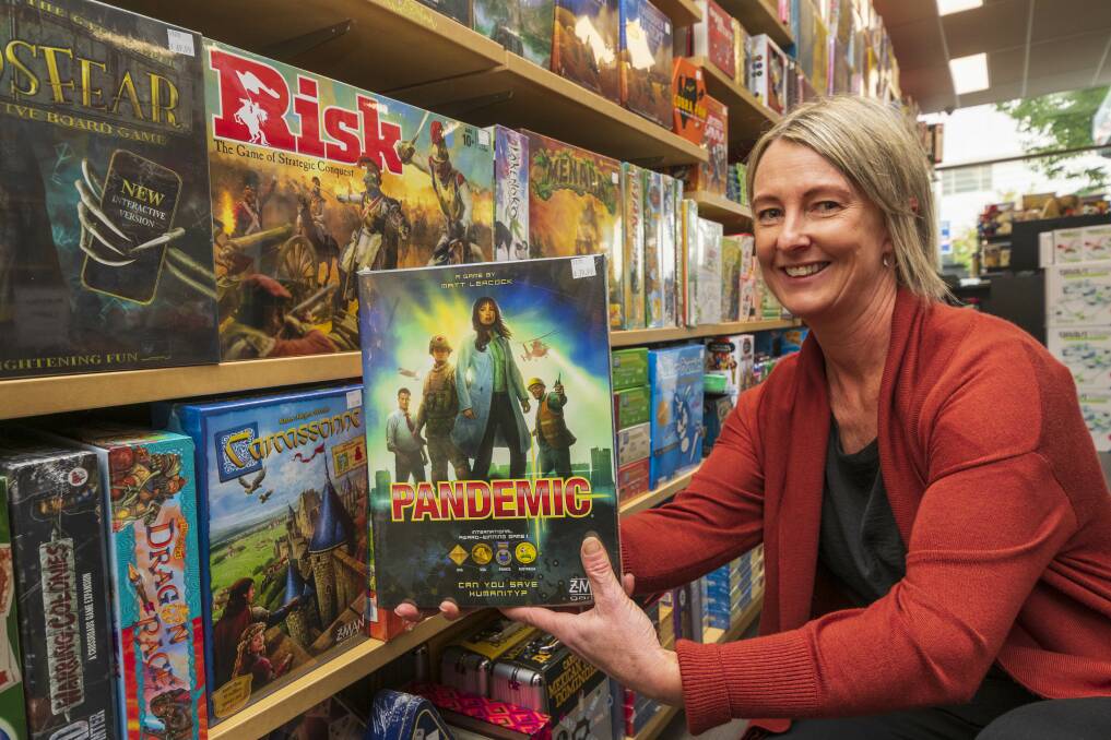 YOUR TURN: Gamesworld Plus shop assistant Kim Templar shows just some of the many board games people can play while stuck indoors. Picture: Phillip Biggs