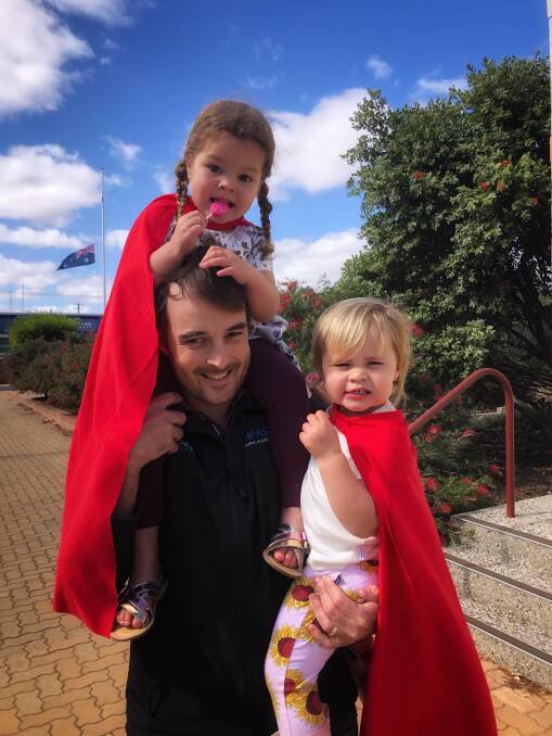 SUPER CUTE: Vivienne and Scarlett Allingham, dressed in super-hero capes, with their dad Mark after receiving influenza injections.