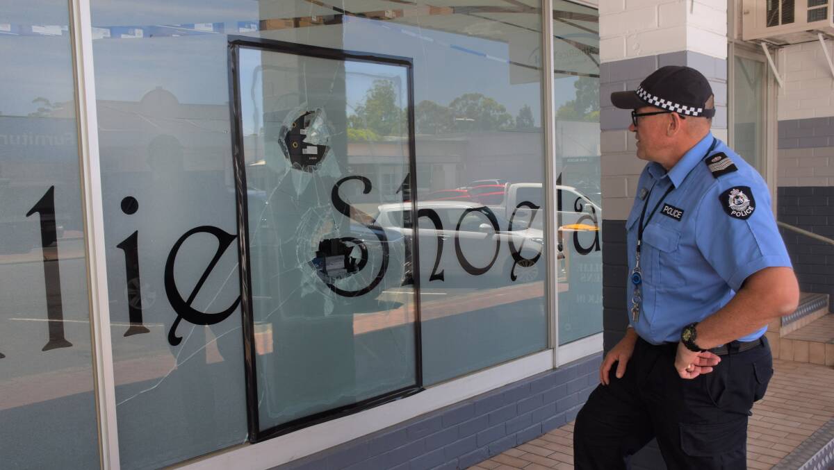 Senior Sergeant Heath Soutar inspects the damage caused to Collie Shoeland. It was just one of four businesses to have its windows damaged in the one night. Photo: Ashley Bolt