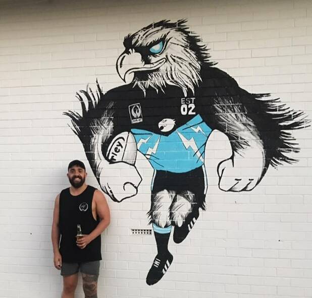 Artist Ash Griggs with the new mural painted on the Collie Eagles' club rooms. Photo supplied.