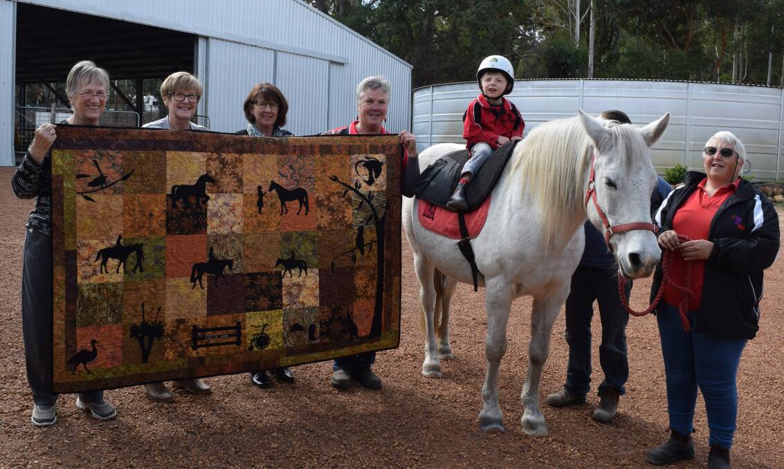 Handcrafted: Collie Art Group members hand the quilt to RDA state president Jo Williams while Travis Read looks on. Photo: Shannon Wood. 