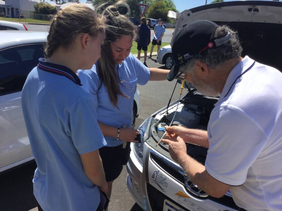 Anika Pelser and Samara Coverley learn about basic vehicle maintenance with Young Driver Development Program instructor Mike Hendry as part of the Collie Senior High School driver safety program. Photo: supplied. 
